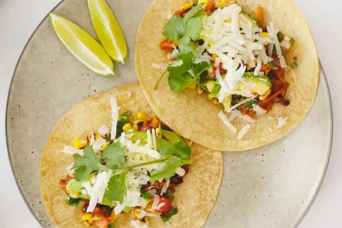 Two pieces tacos with slices of lime on the side.