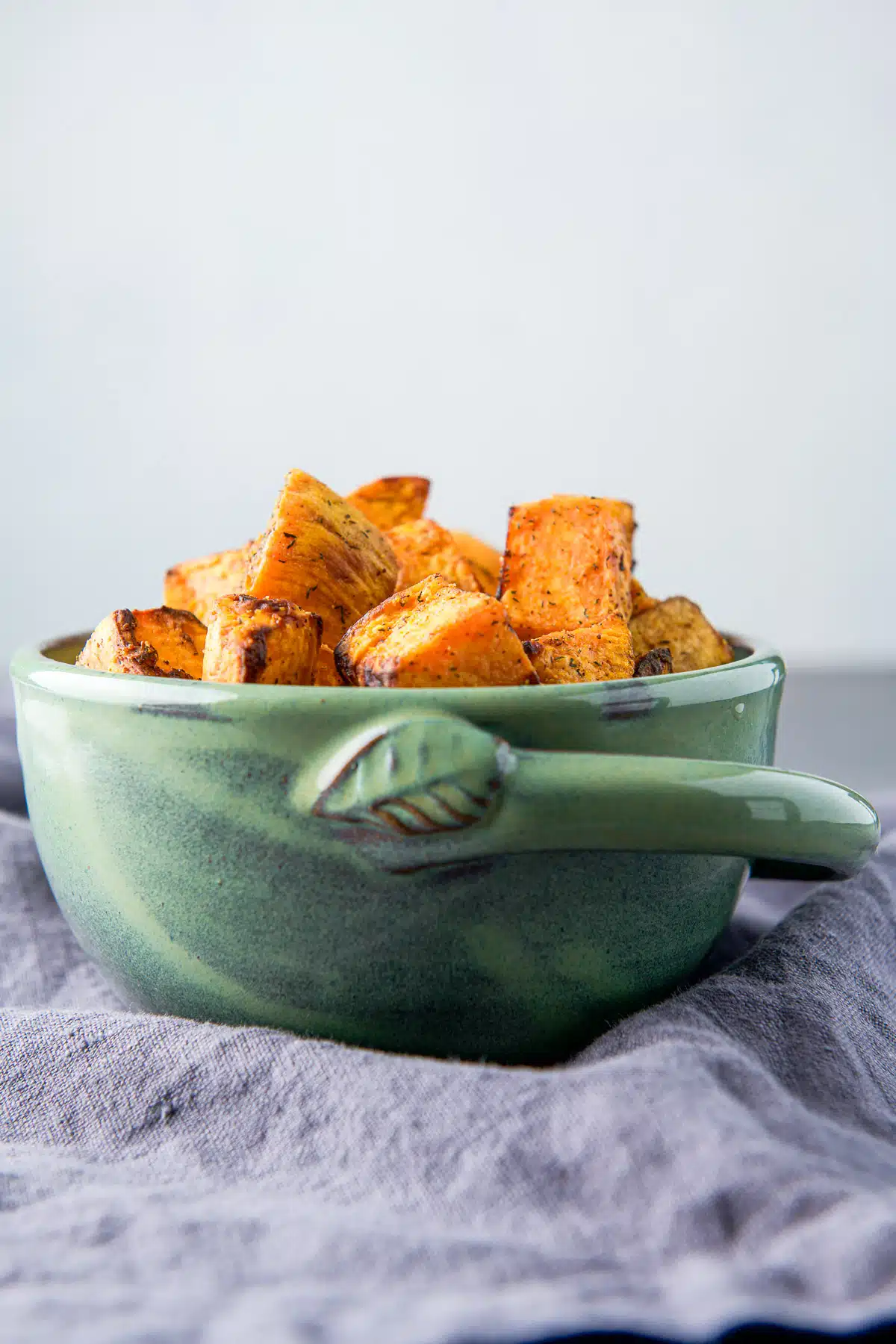 vertical view of a green bowl of sweet potatoes