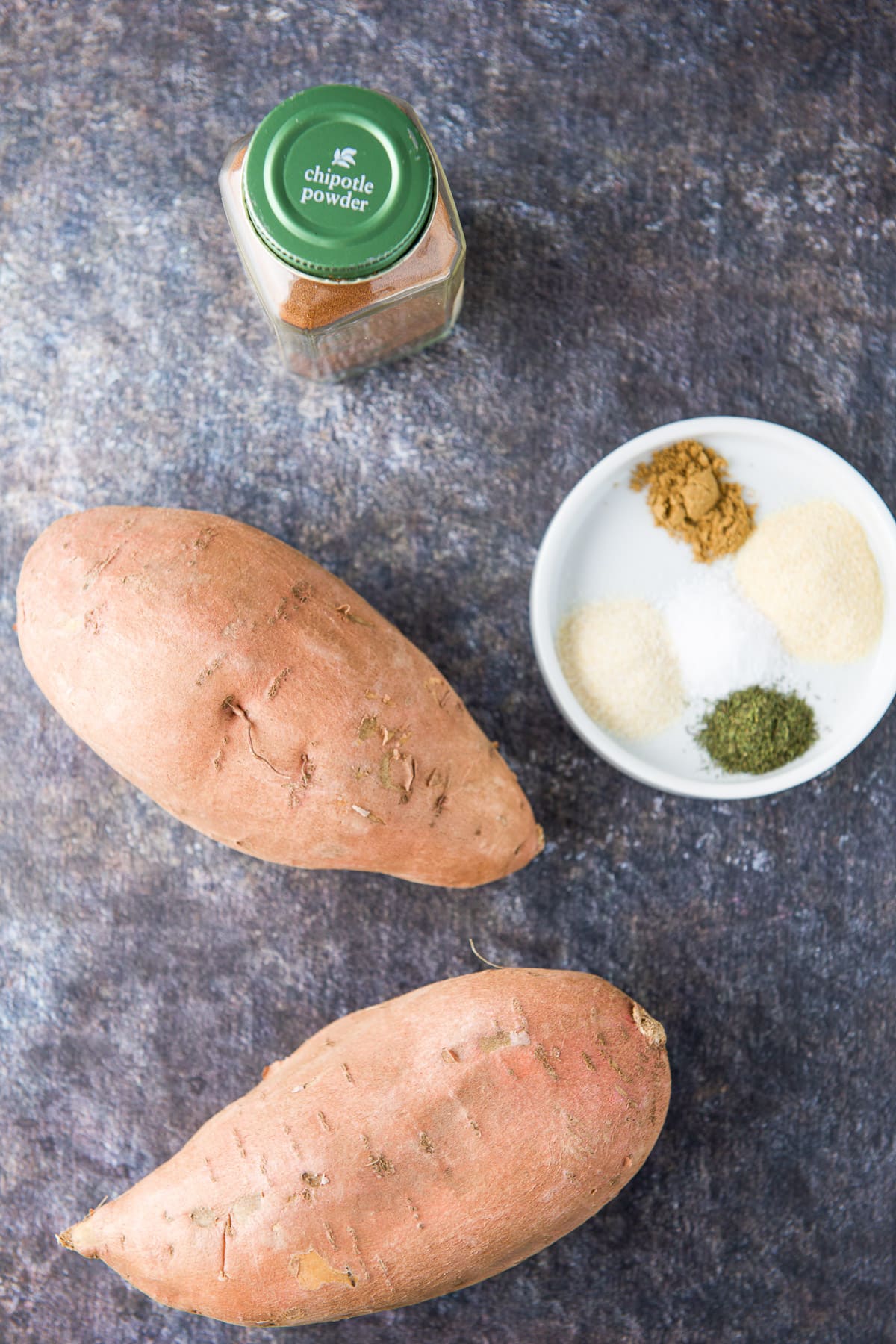 Sweet potatoes, chipotle powder, and herbs and spices in a white dish