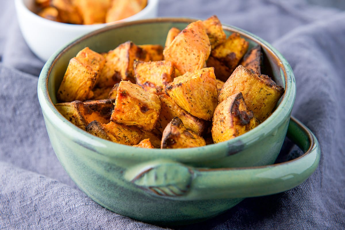 A green bowl with cubes of cooked sweet potatoes in it - horizontal