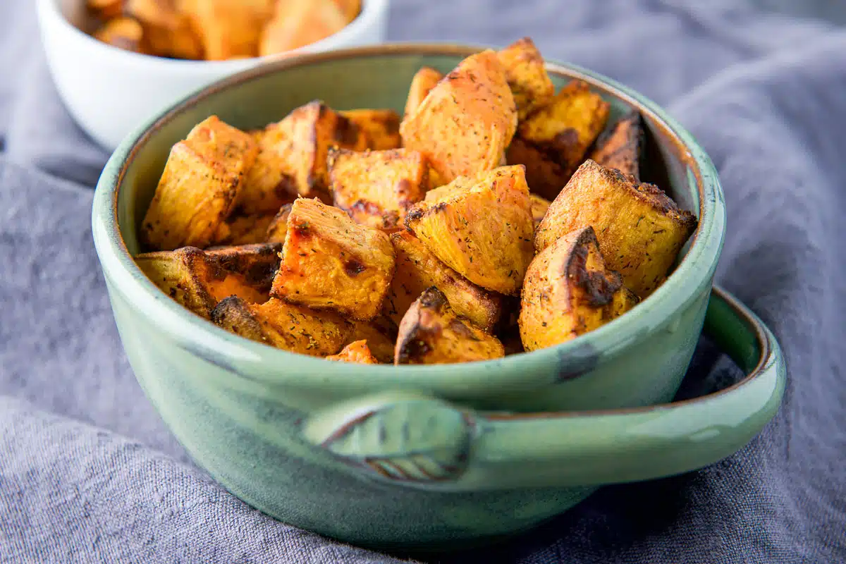 A green bowl with cubes of cooked sweet potatoes in it - horizontal