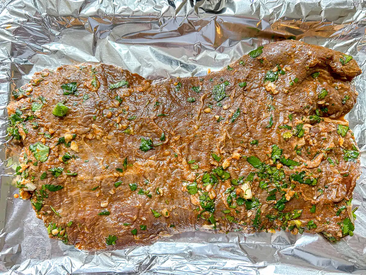 Flank steak on a foil lined pan with cilantro on top