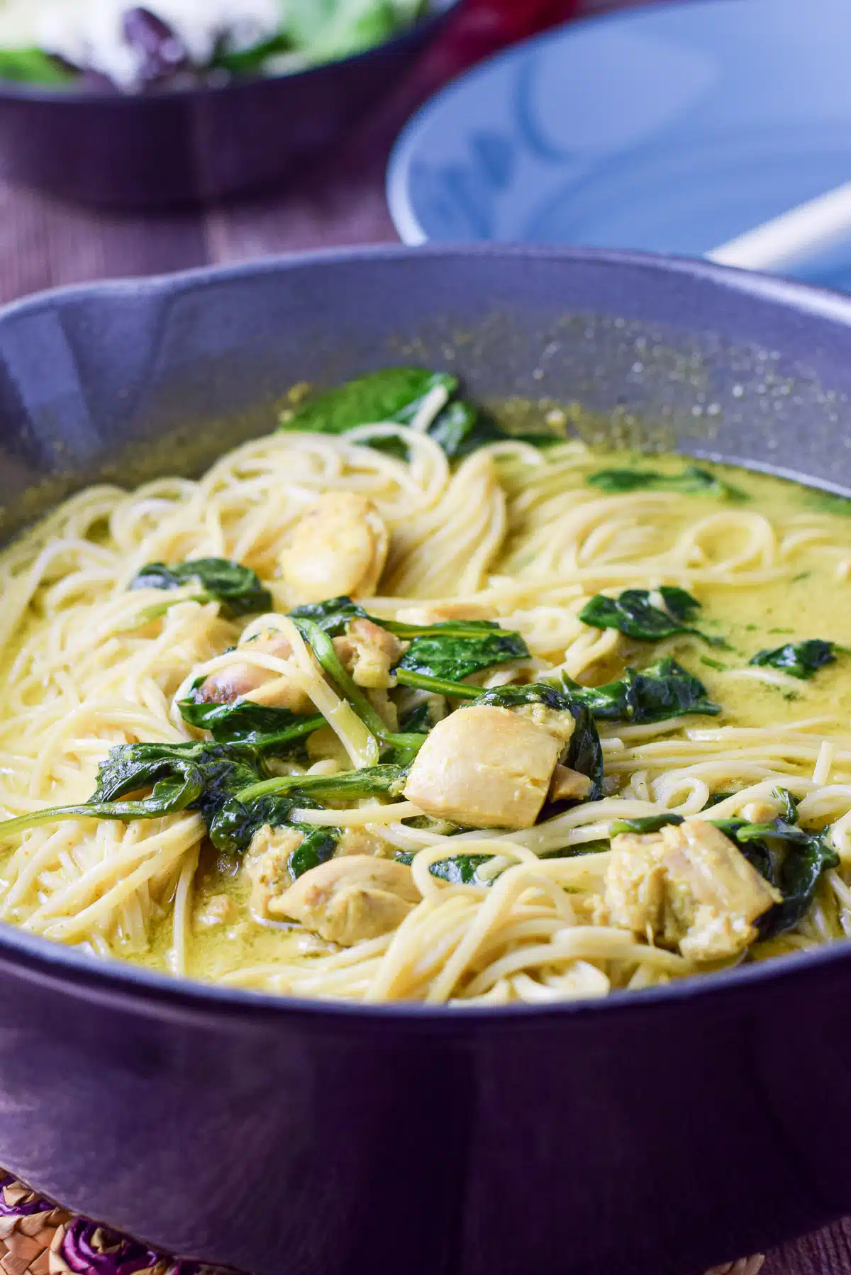 A pan with curry sauce, noodles, spinach and chicken