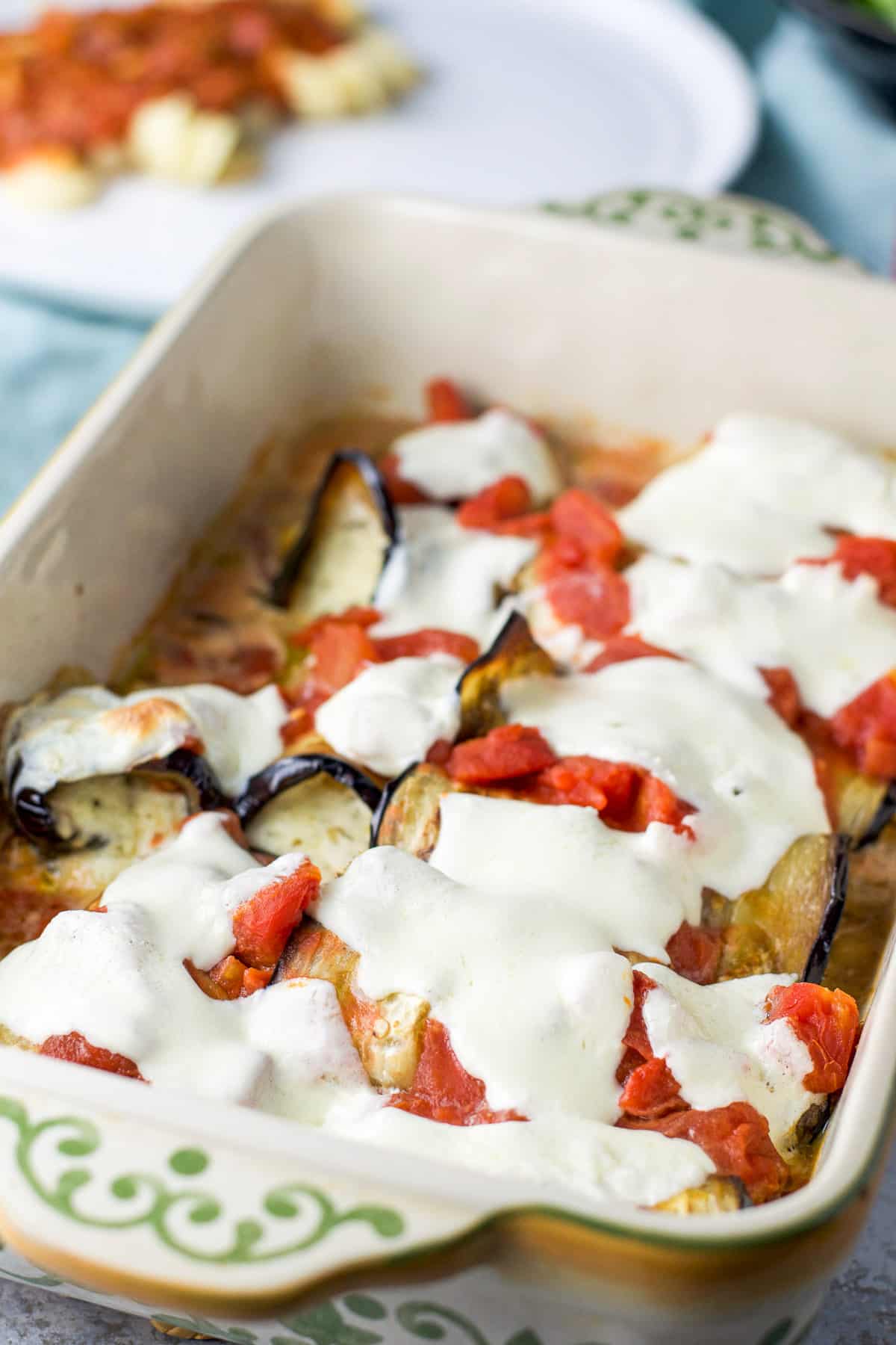 Pan of rolled up eggplant fresh out of the oven with melty cheese on top