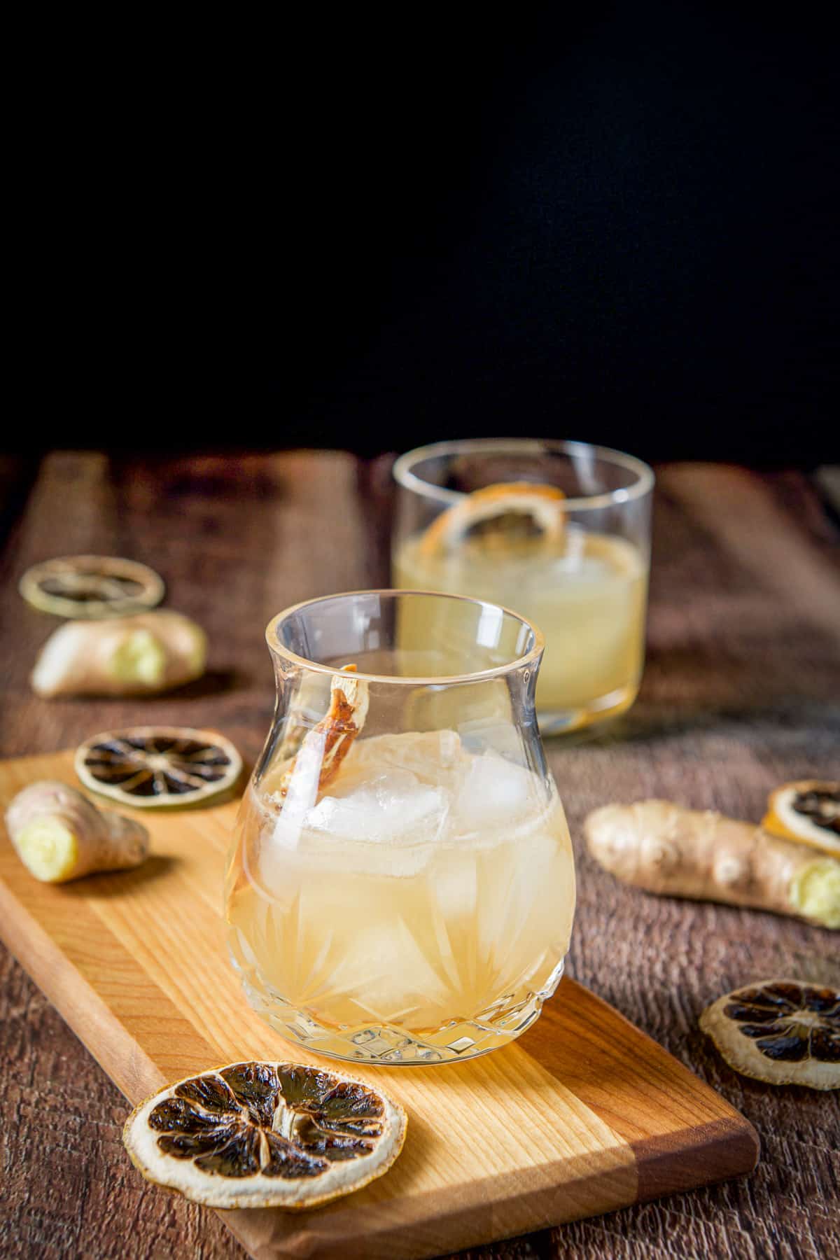 A beautiful faceted glass on a board with another glass in the back filled with the cocktail