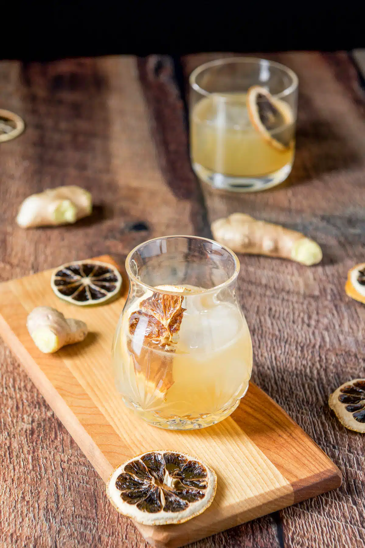 dried lemon wheels in two cocktail drinks with ginger in the back along with more wheels