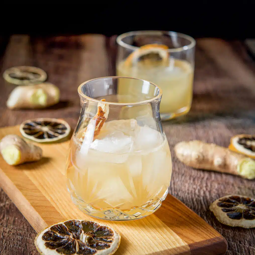 Two glasses on the table, on one a board with ginger root and sliced dried lemons