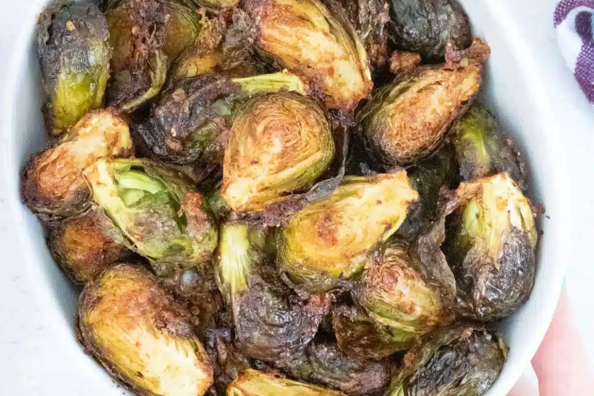 A white bowl with roasted Brussels sprouts in it - all cut in half