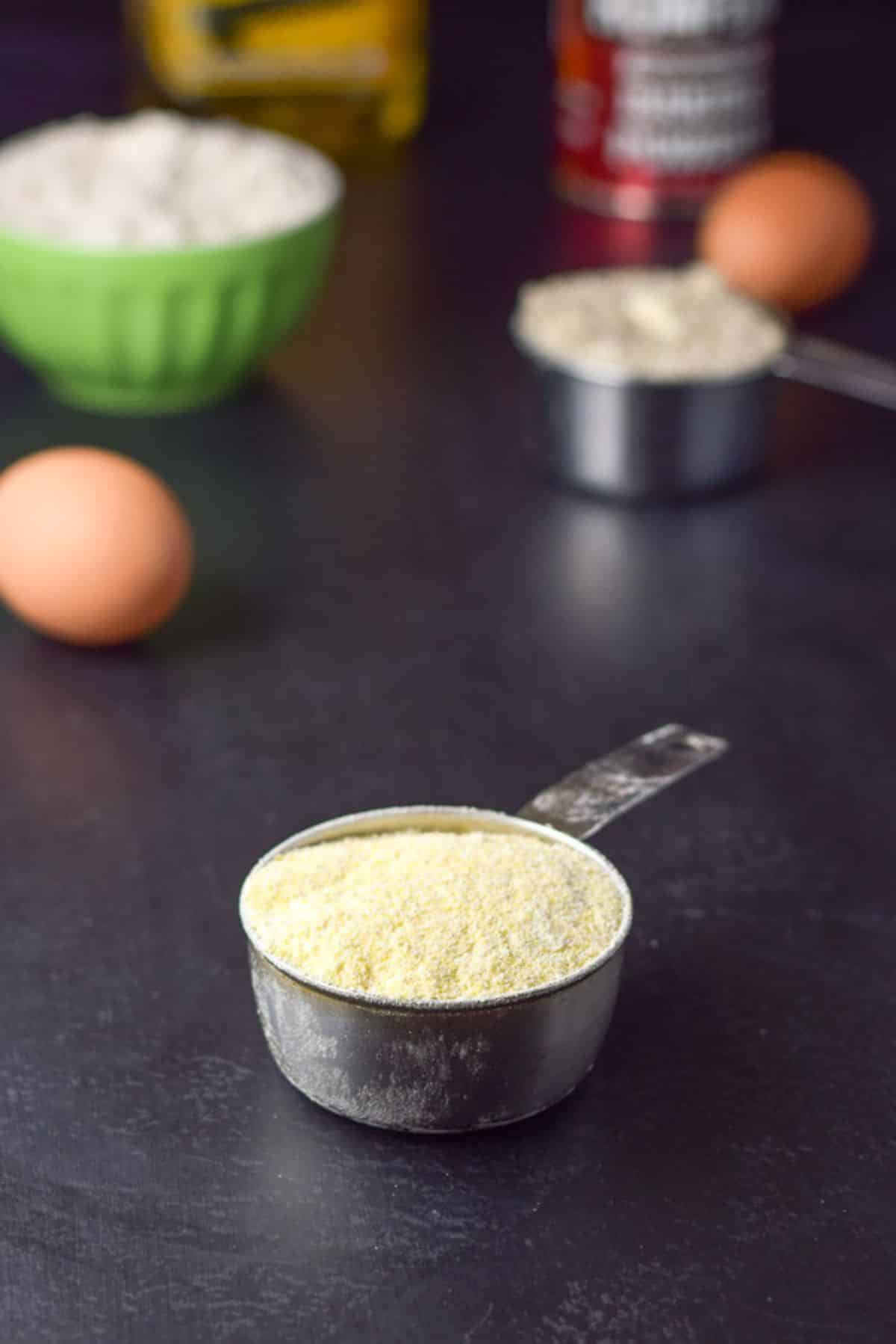 Corn meal, eggs, flour, baking powder and oil on a black table