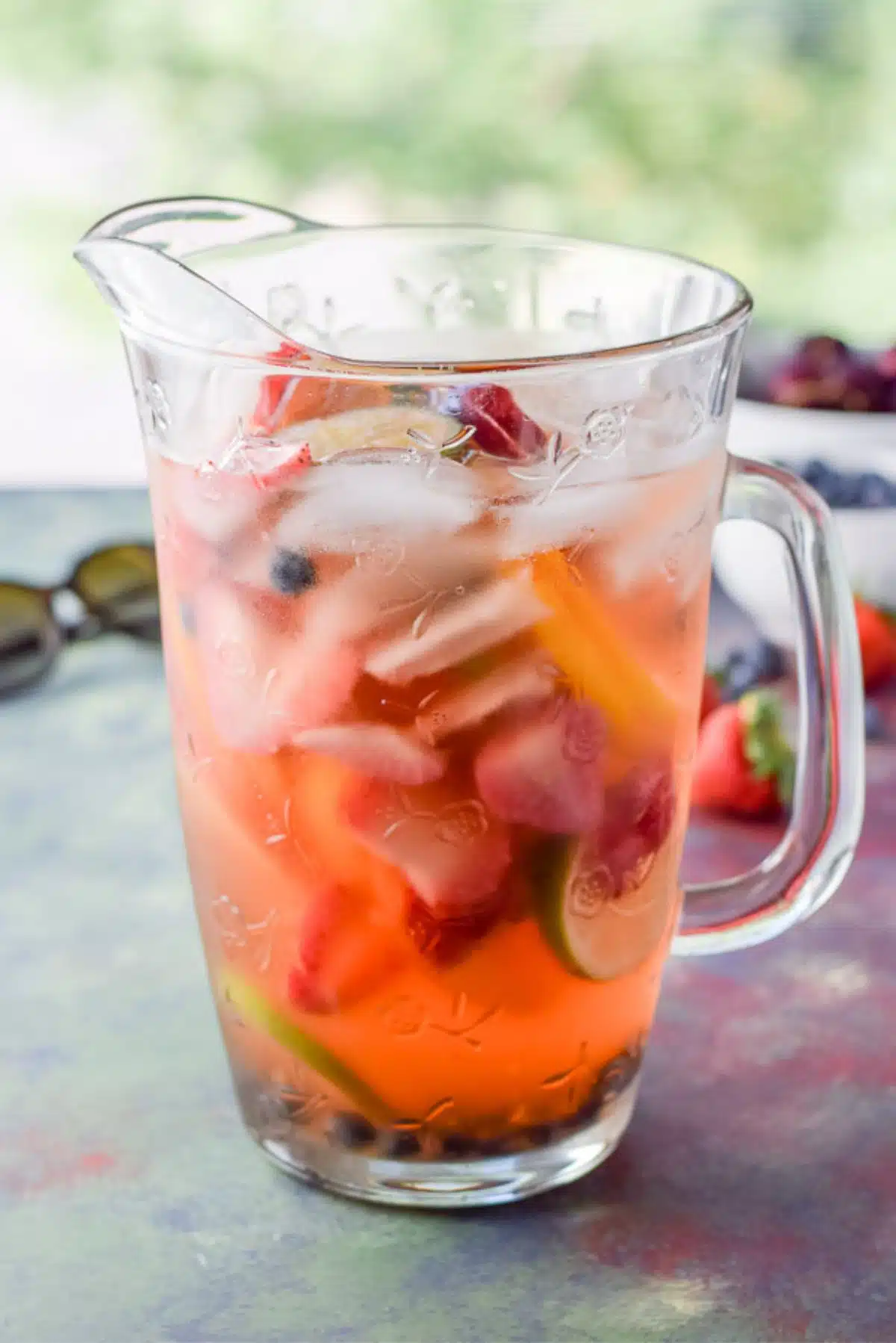 Pitcher of the sangria with strawberries, blueberries and cherries in the background