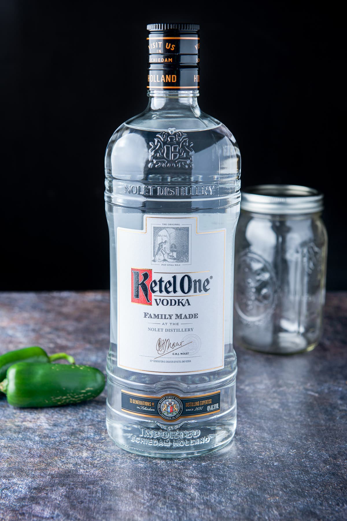 Vodka, jalapenos, and a jar on a table