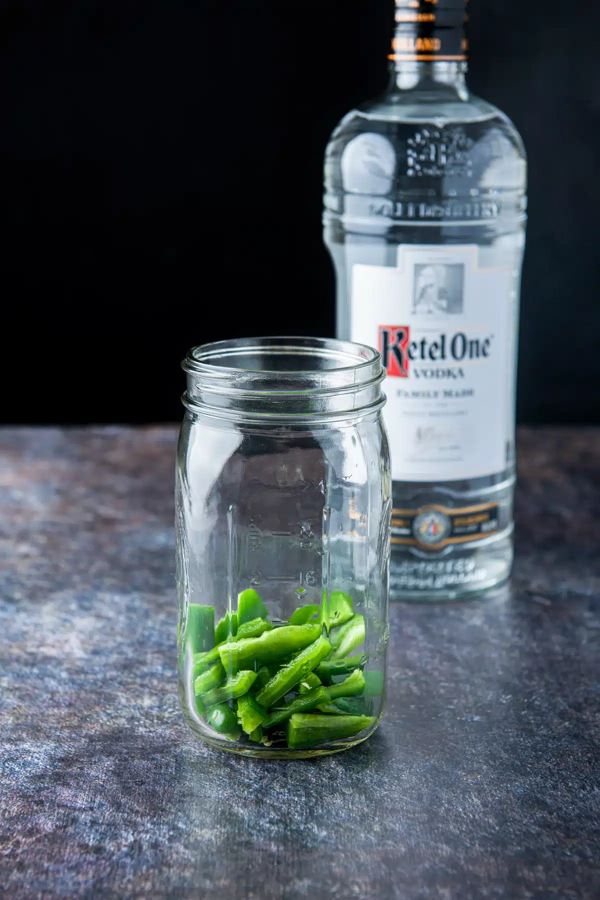 Jalapeno cut up, deseeded, and put in the jar with vodka in the background