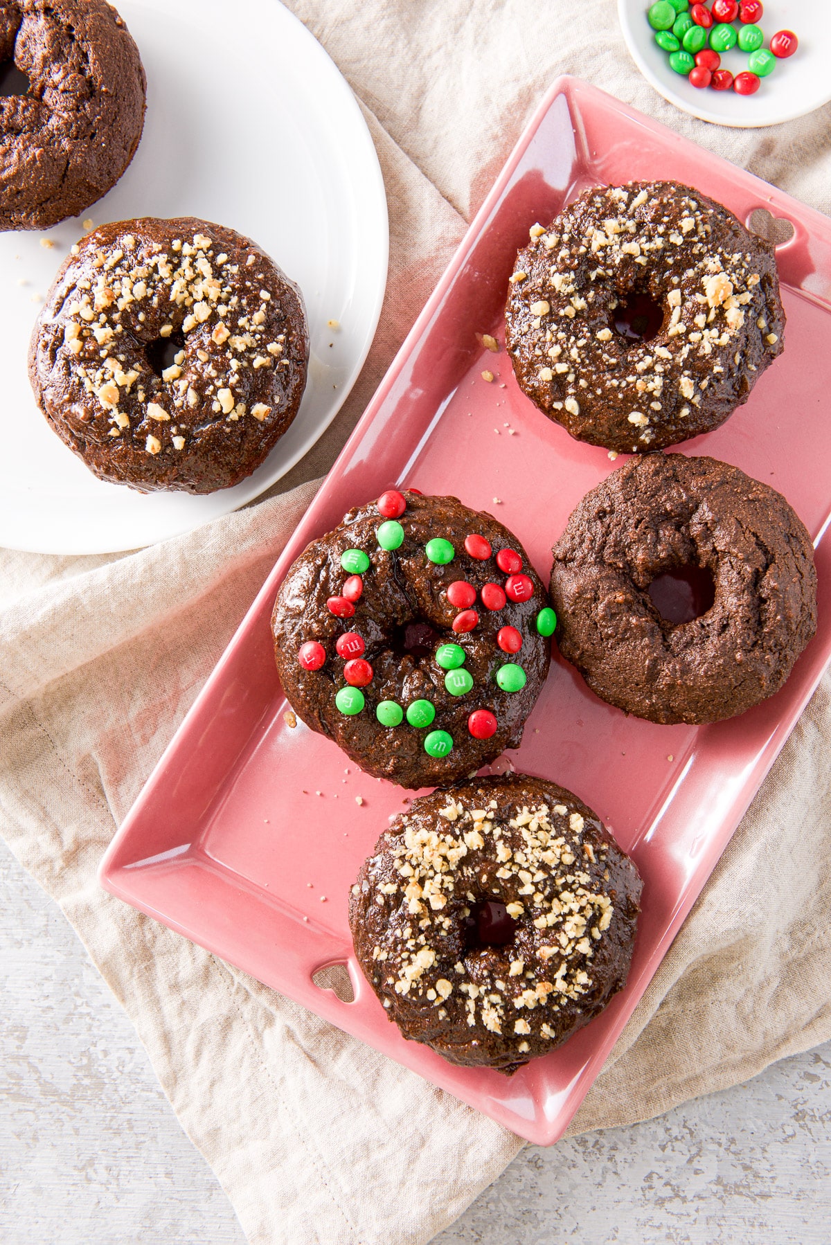 overhead view of the pink platter with four donuts on it along with a white plate with more