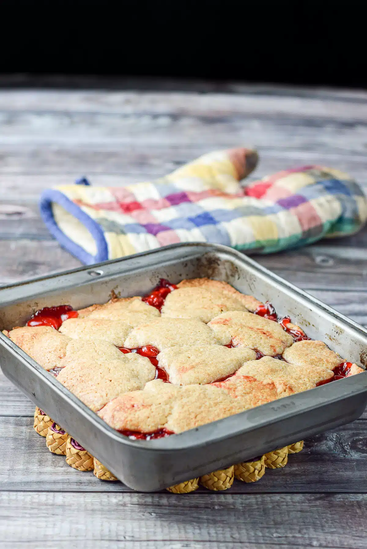The cherry dessert straight out of the oven cooling on a trivet