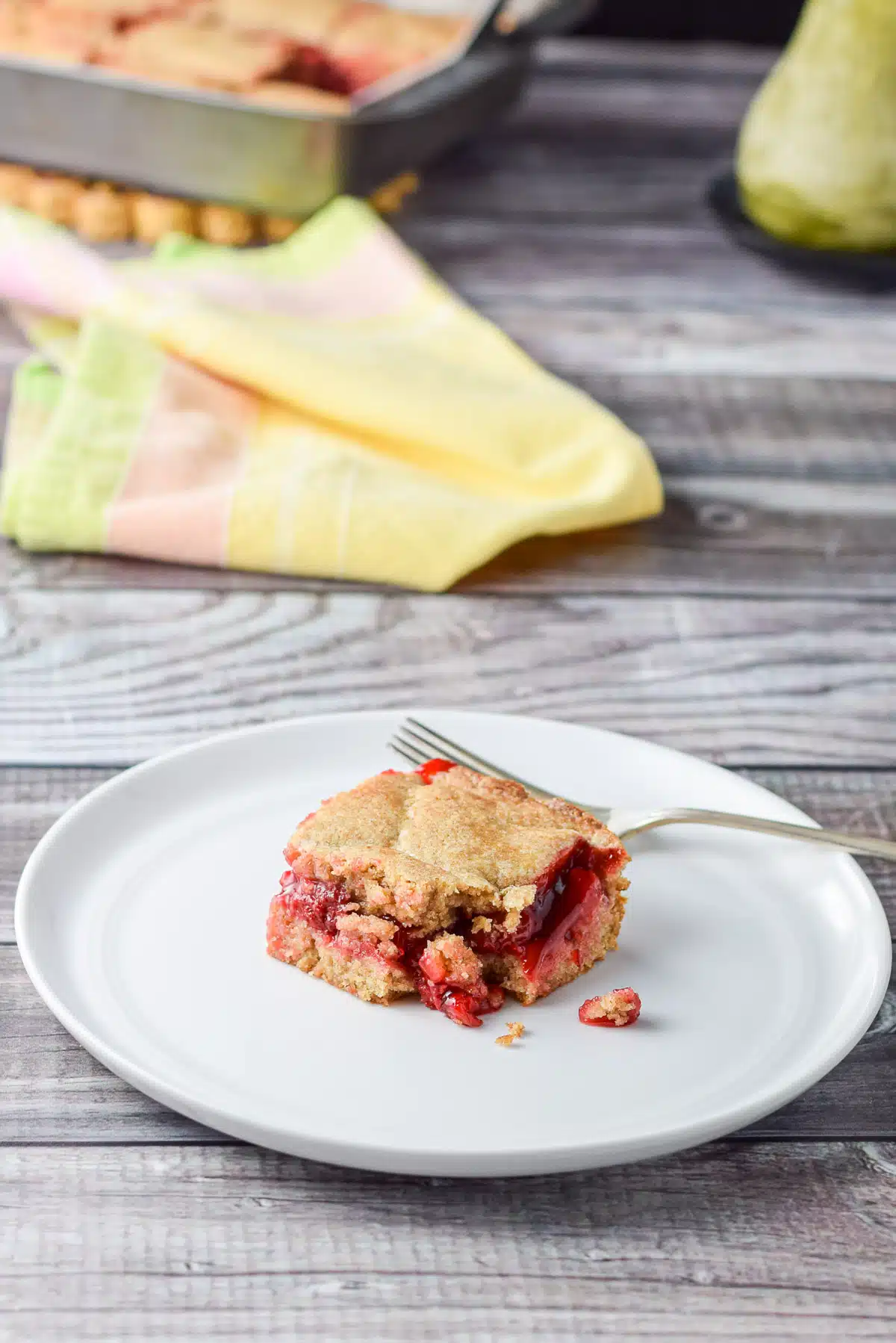 A bite taken out of my cherry squares with the pan in the background and a fork on the plate