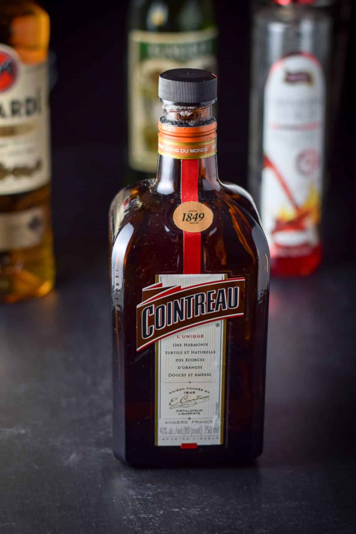 Cointreau, rum, vermouth, and grenadine on a black background
