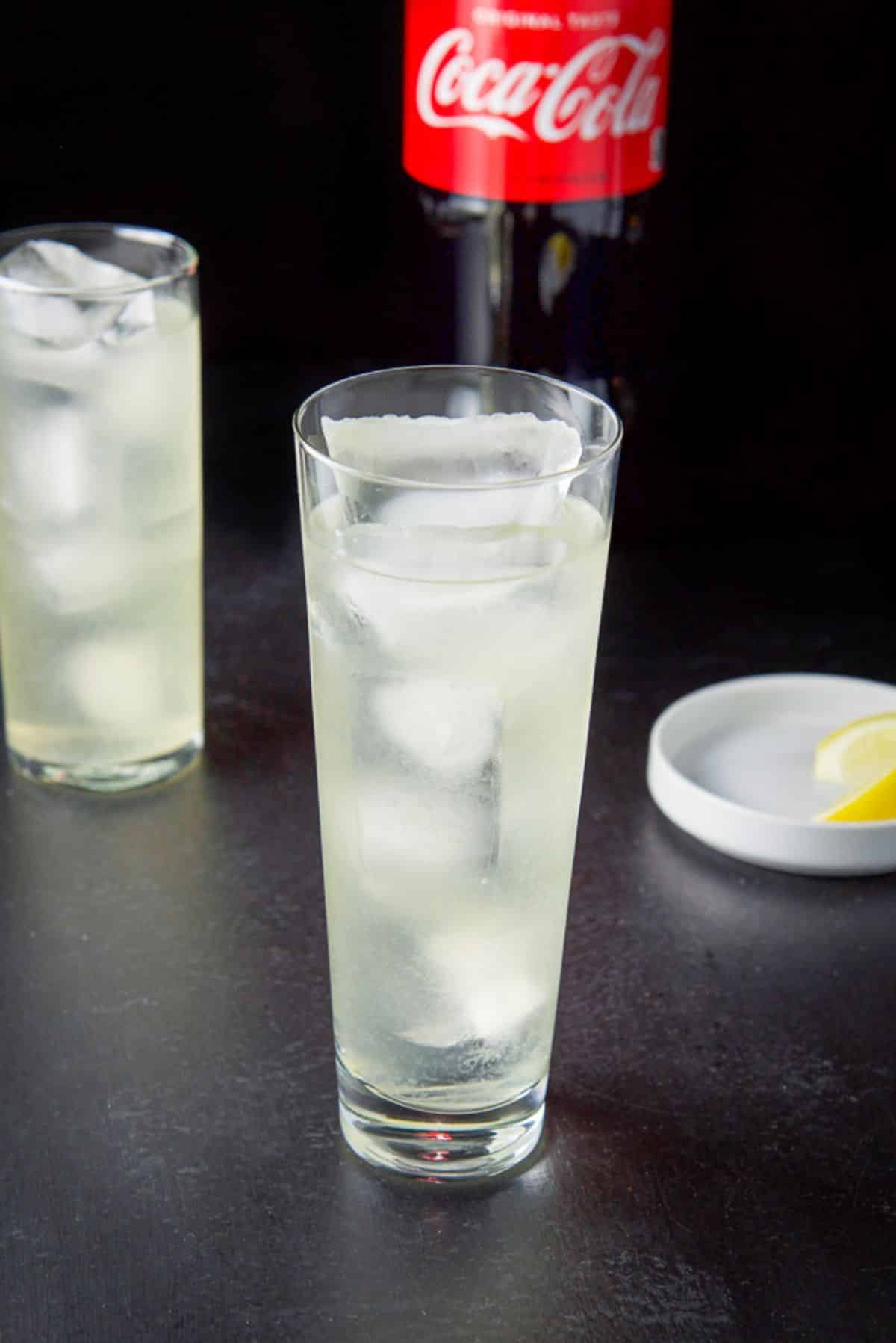 Everything but the coca cola poured in the glasses with a few lemon wedges in a white dish