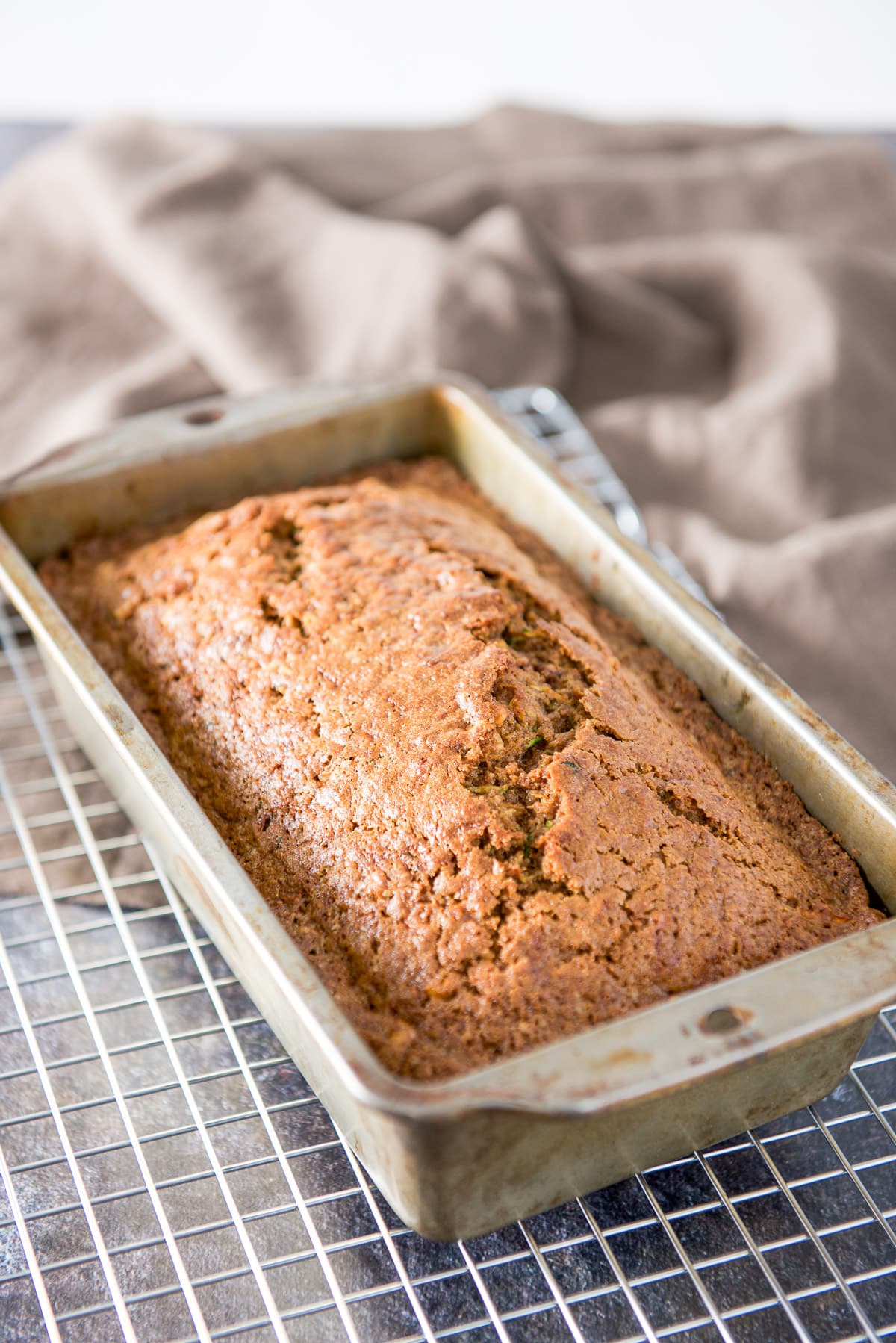 The zucchini bread fresh out of the oven still in the pan but resting on a wire rack