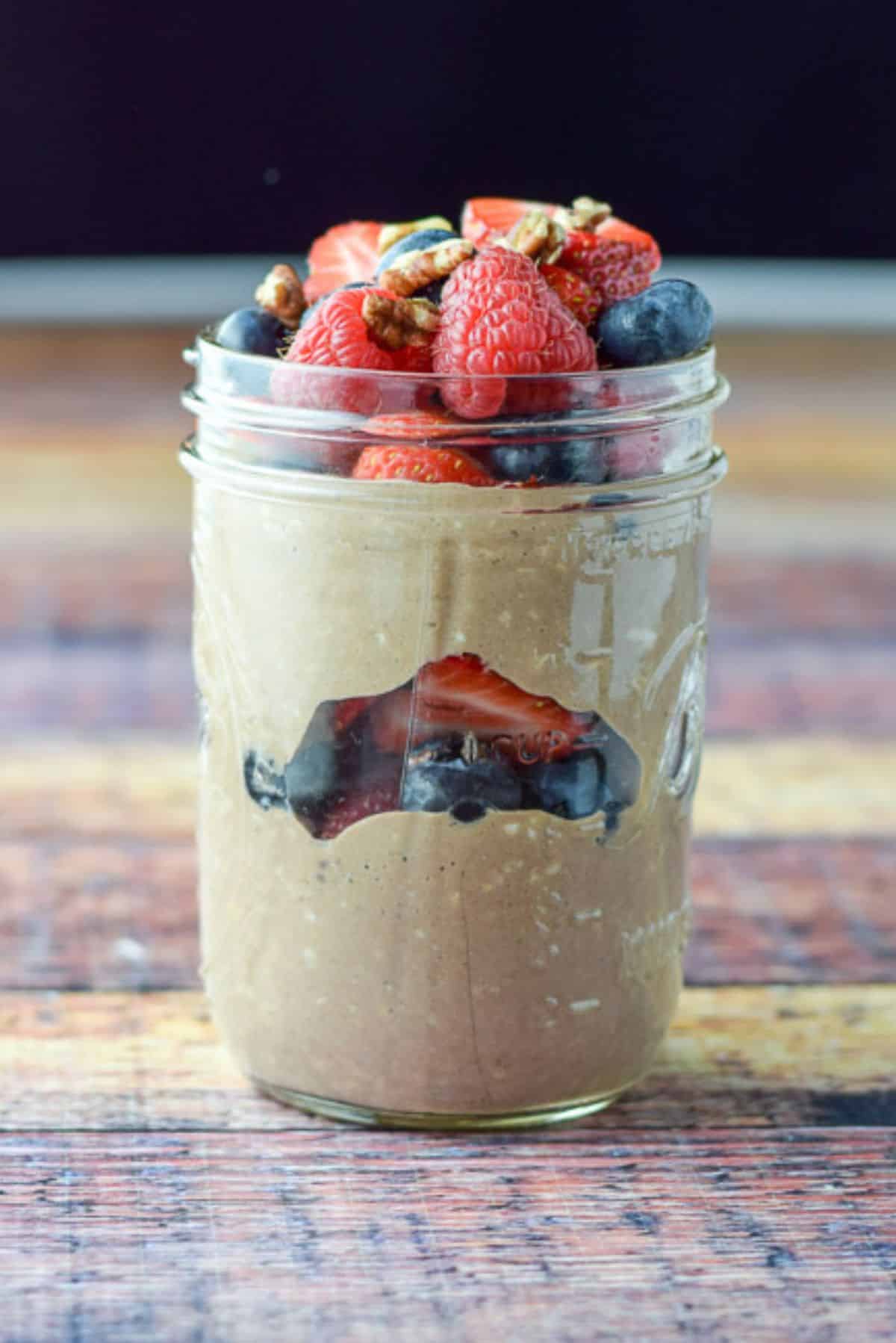 Vertical view of oats in the jar with berries in layers