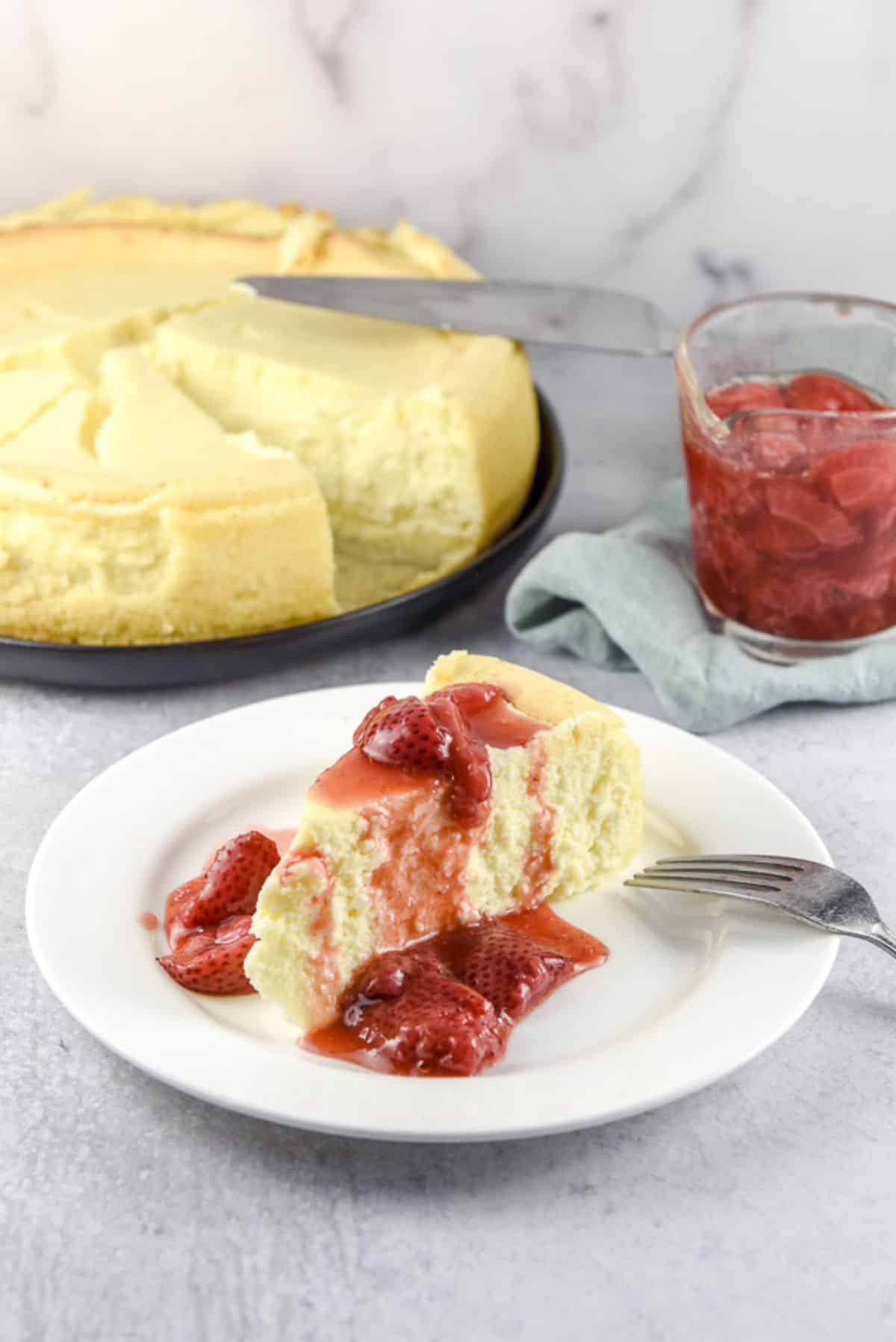 Strawberries draped on a piece of cheesecake - with the sauce and cake in the background