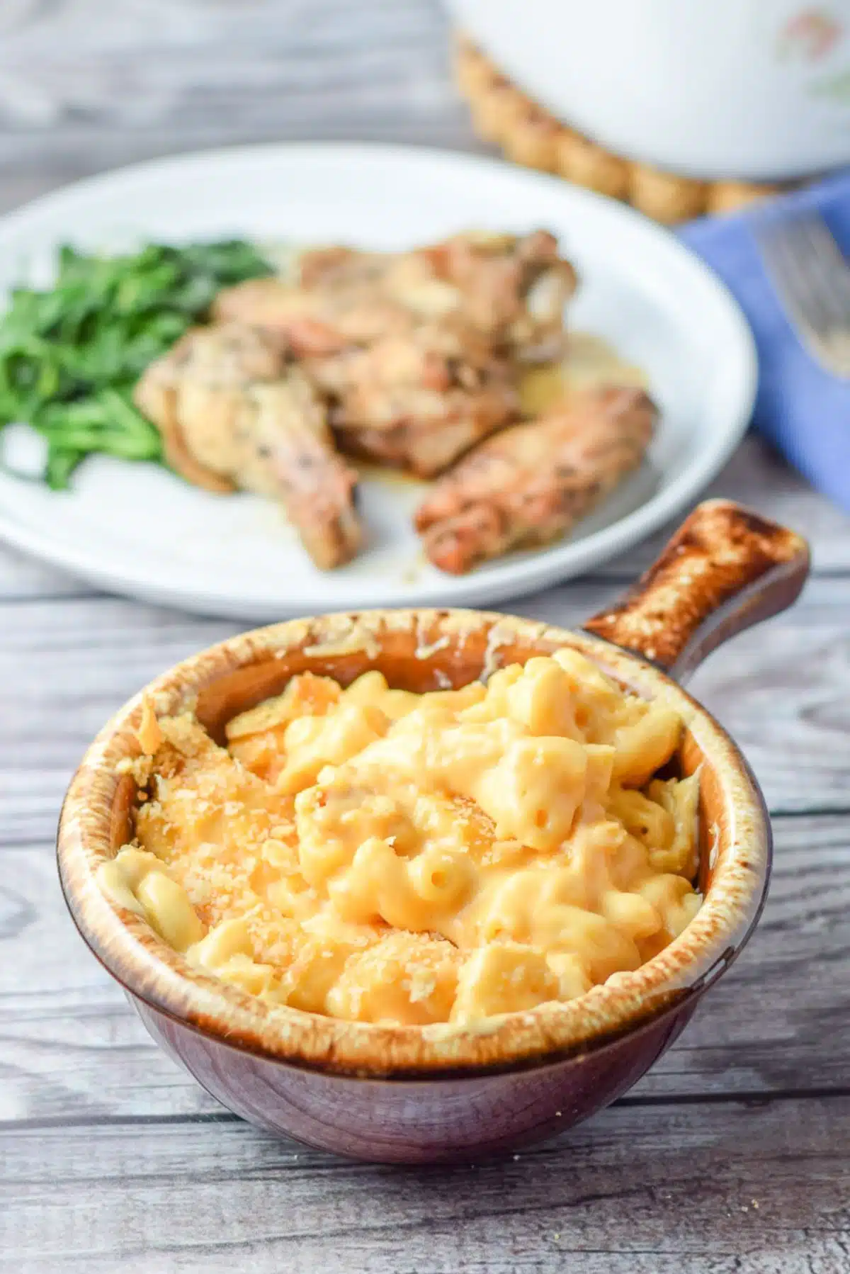A plate of food behind a brown crock of mac and cheese