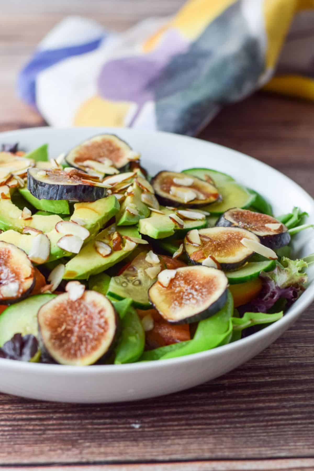 A white shallow bowl with all the ingredients to the salad on a wooden table