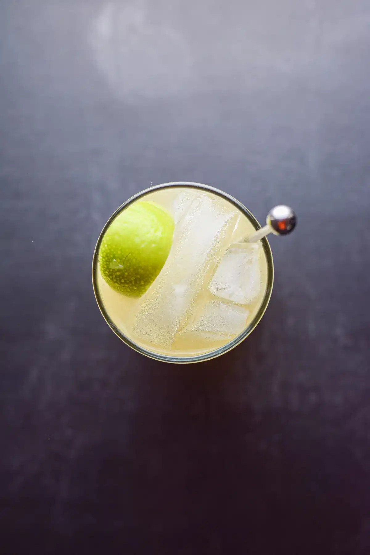 Overhead view of the glass with the stirrer, ice and lime wedge