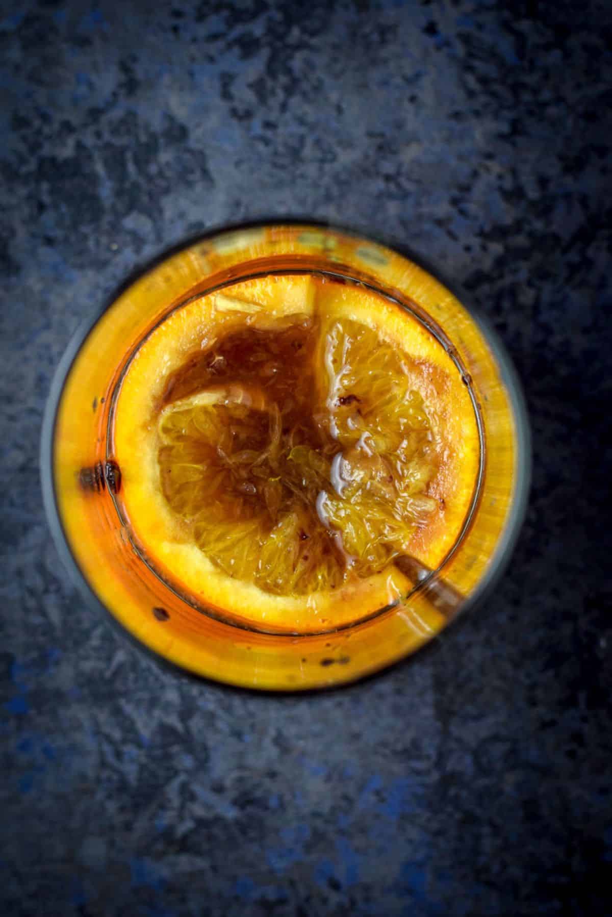 Orange slice and cherry muddled in the bottom of a cocktail shaker
