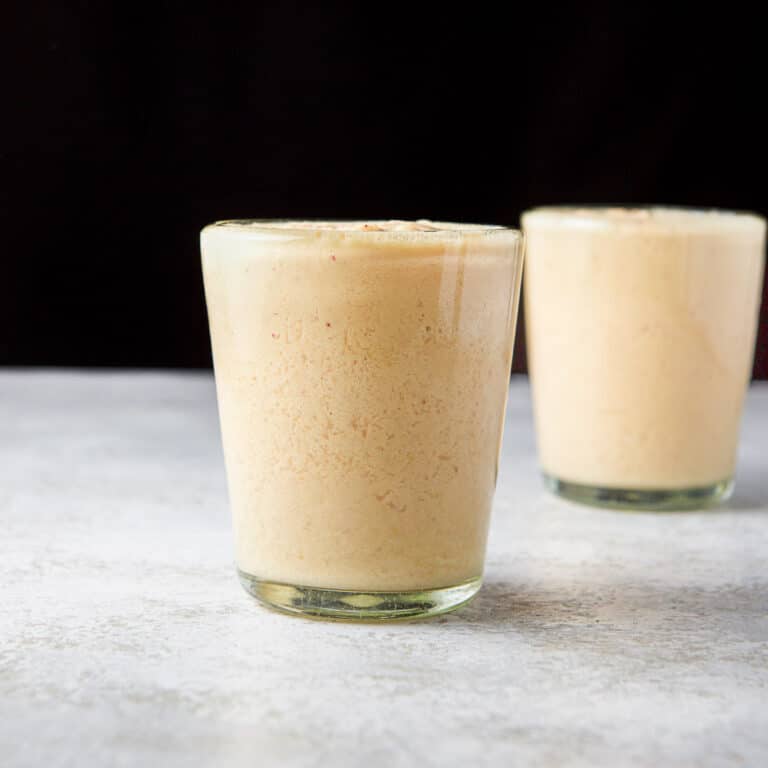 square photo of two glasses with the mango smoothie in them