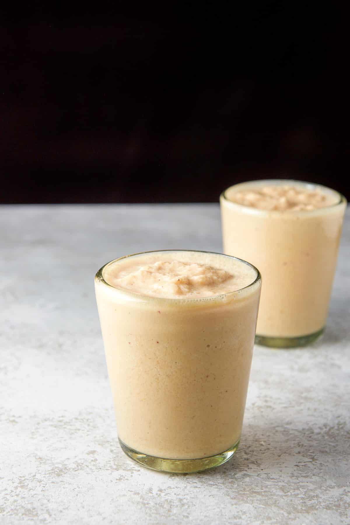 Two glasses filled with the orange-colored smoothie on a table