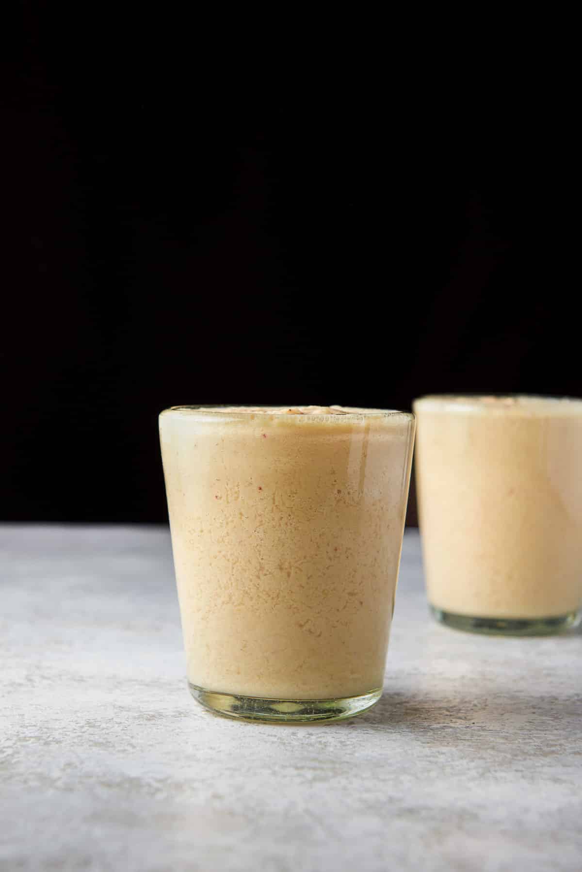 Vertical view of two glasses filled with the mango smoothie