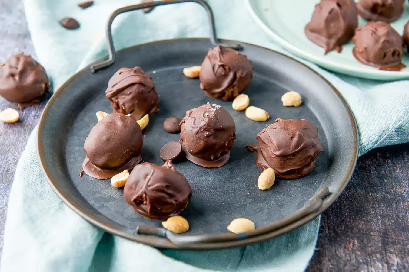 horizontal photo of peanut butter balls on a tray with others in the back