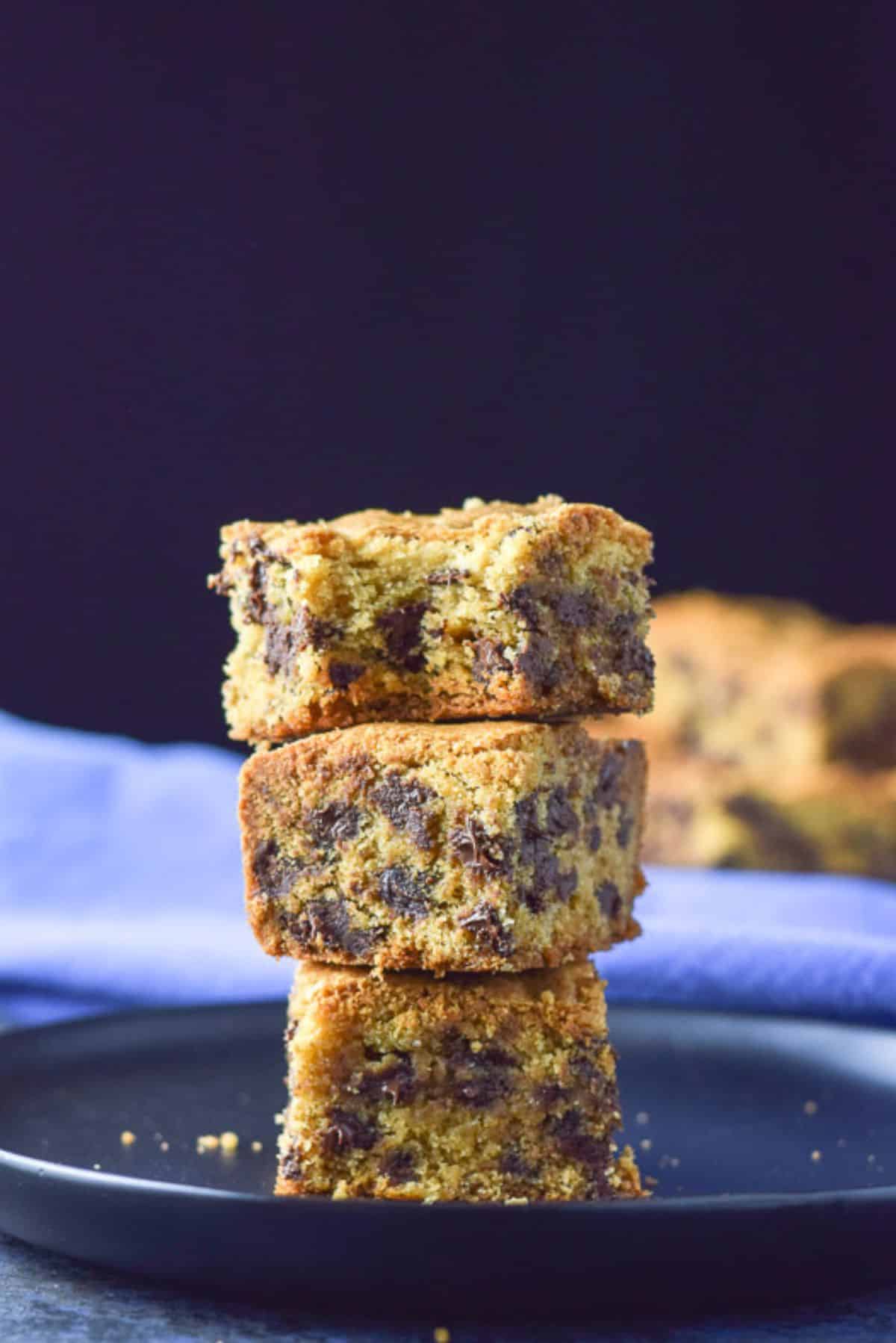 A pile of three bars with the top one with a bite taken out of it all on a black plate