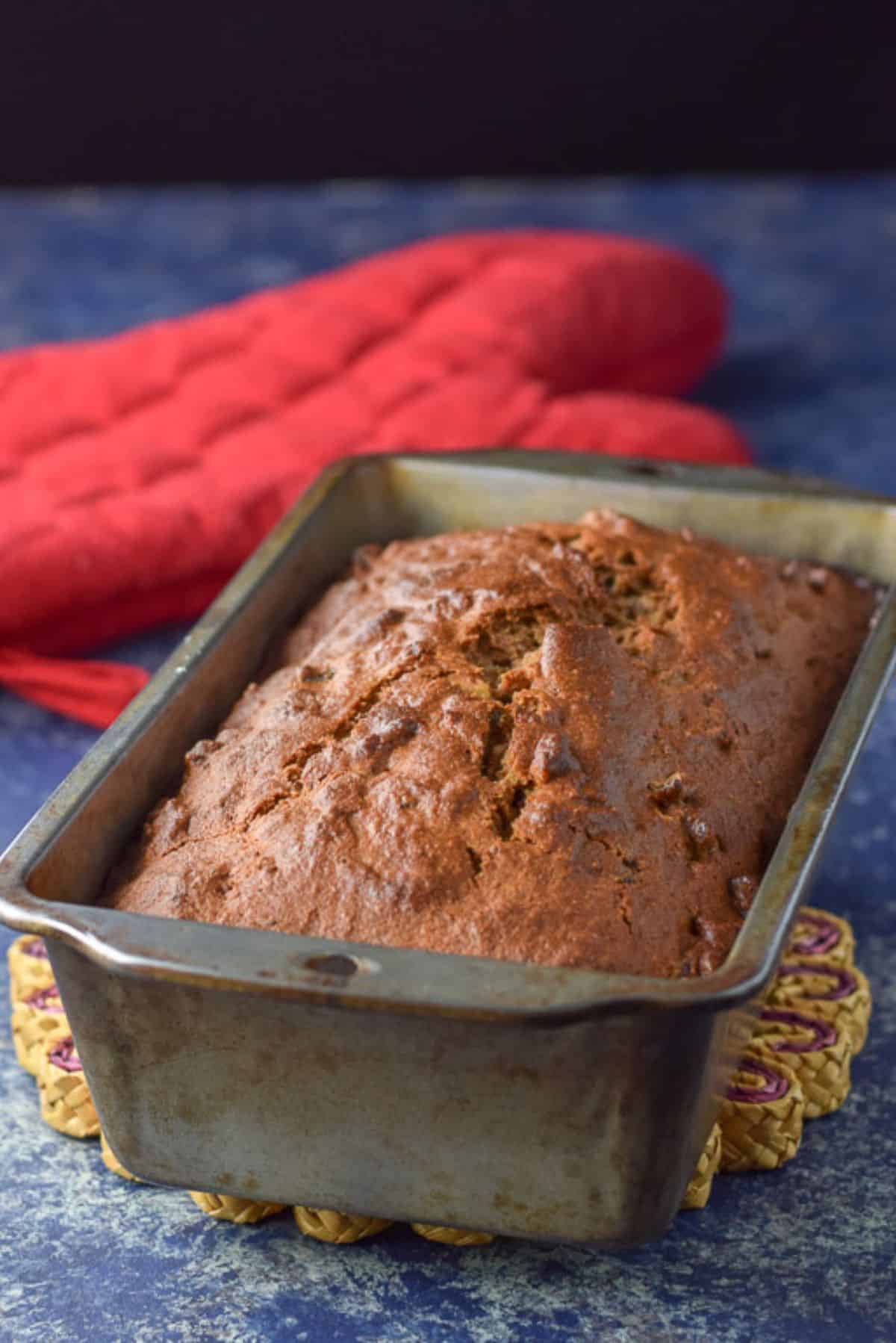 Sweet bread straight out of the oven with a red oven mitt in the background
