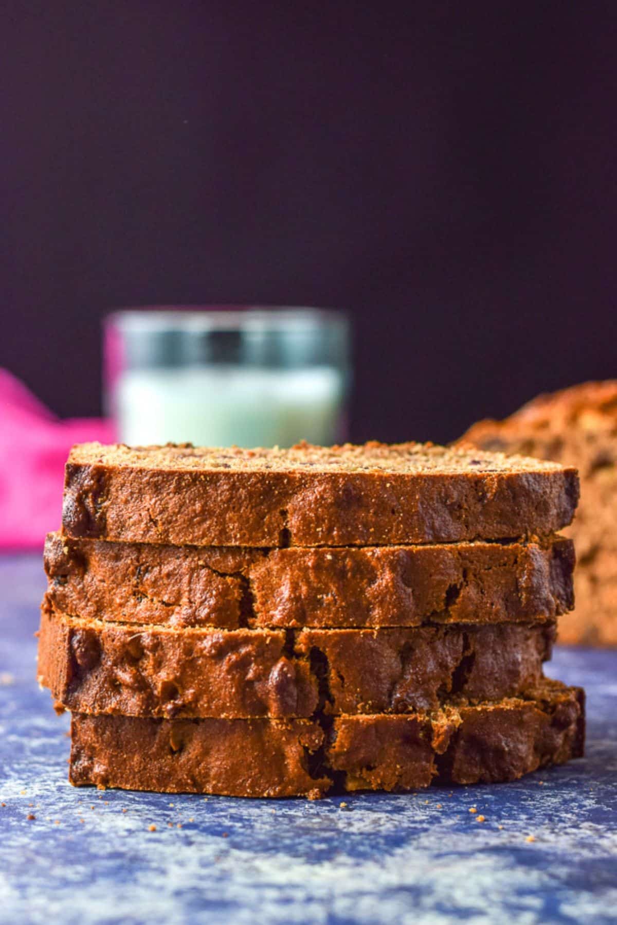 Vertical view of four slices of bread stacked on each other with the loaf over the side