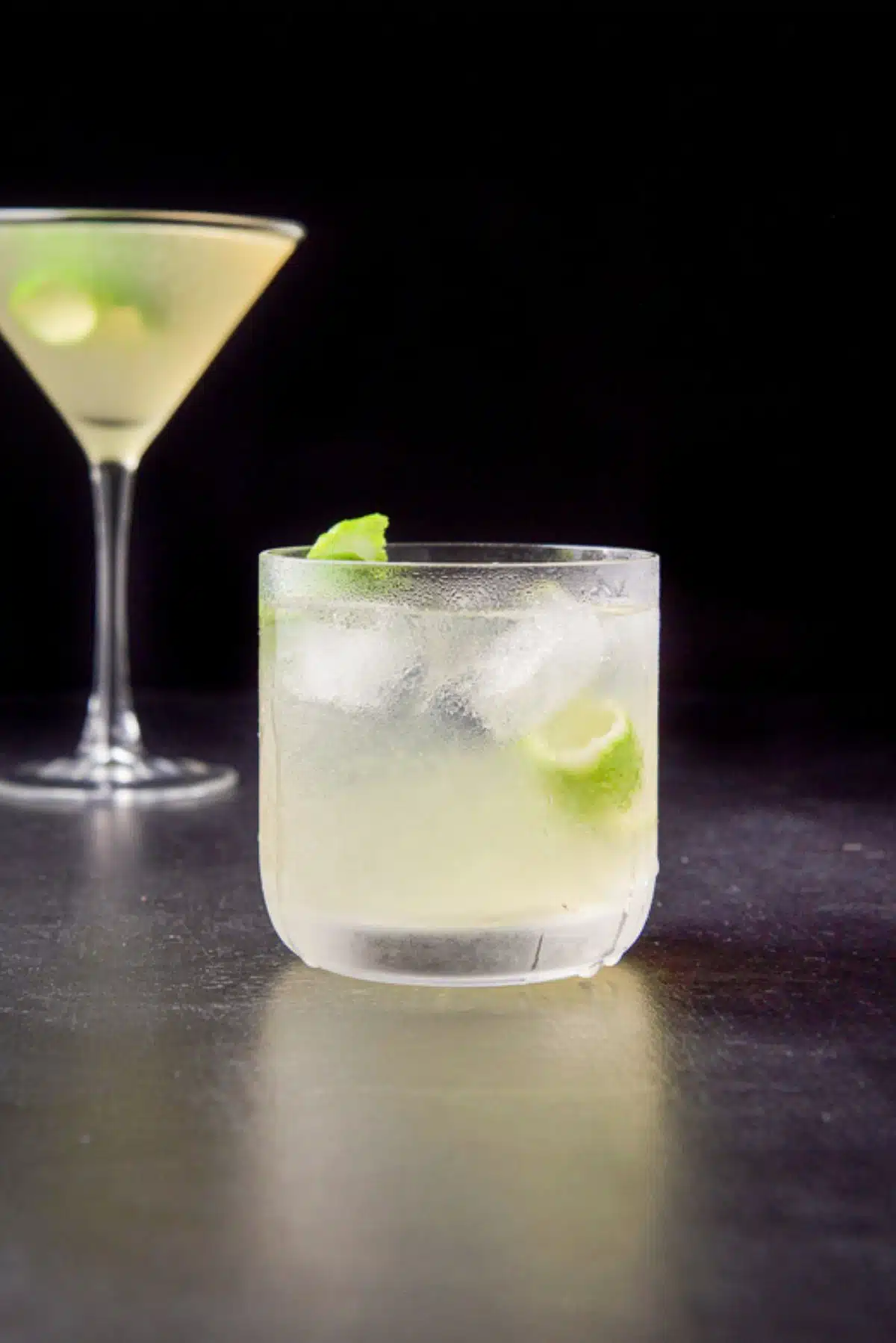 Vertical view of the gimlet in the old fashioned glass in front of the classic martini glass