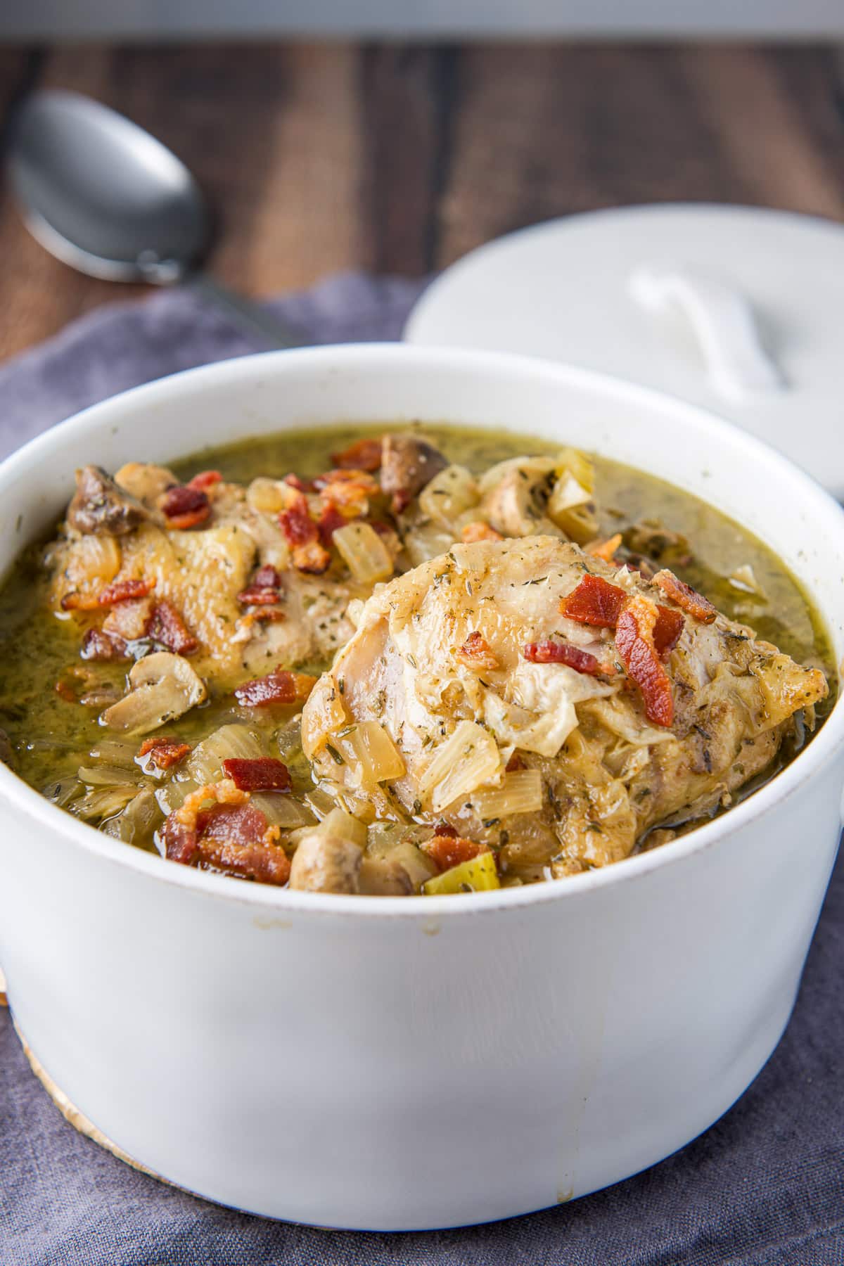 A white pan filled with coq au vin with extra bacon on top