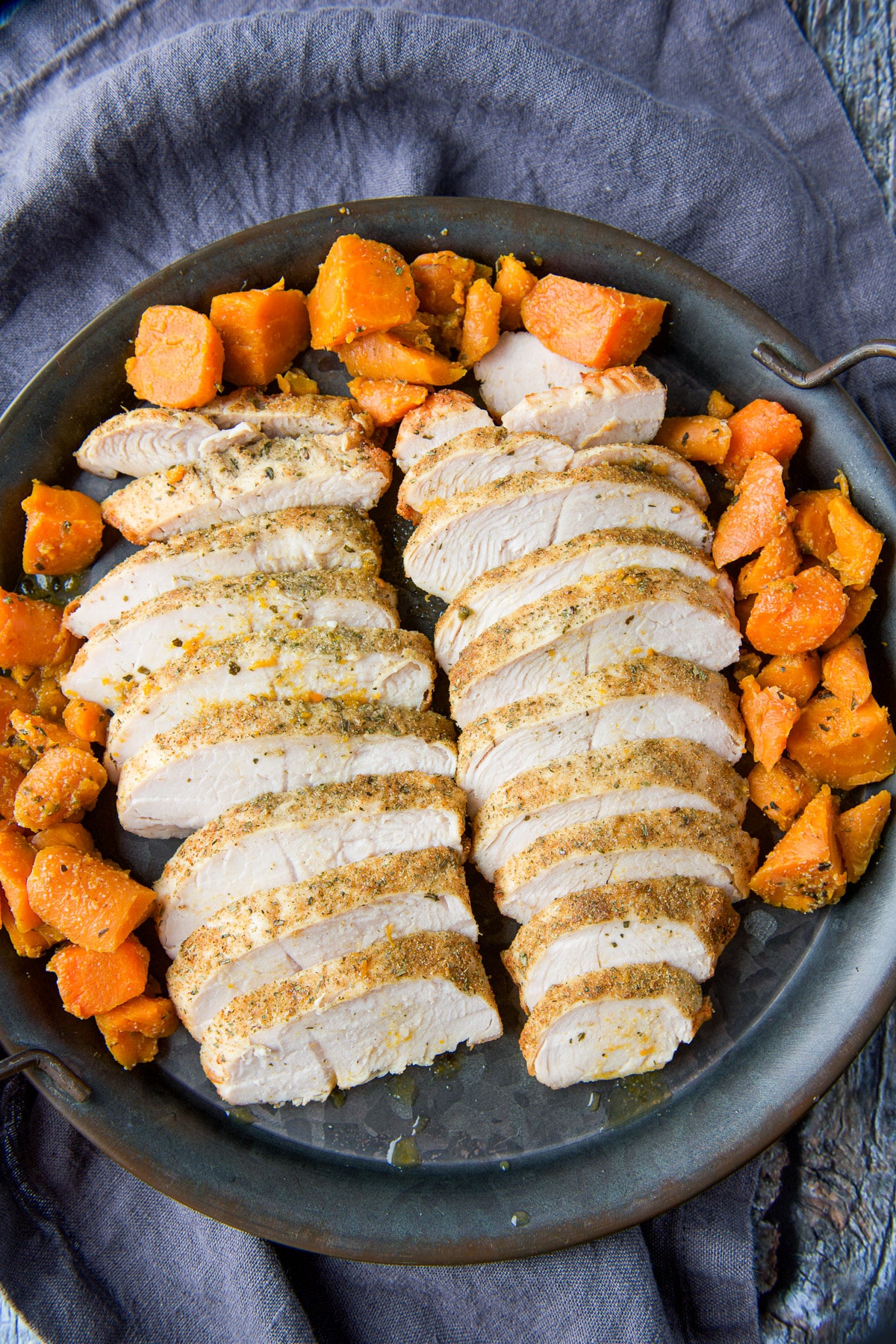 Overhead view of a metal plate with carrots and slices of turkey tenderloin