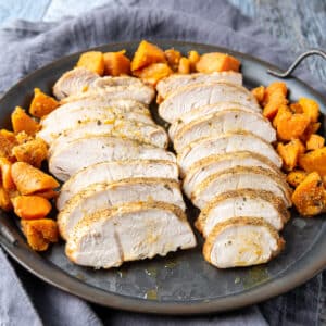 Square photo of a metal plate with slices of turkey and cooked carrots