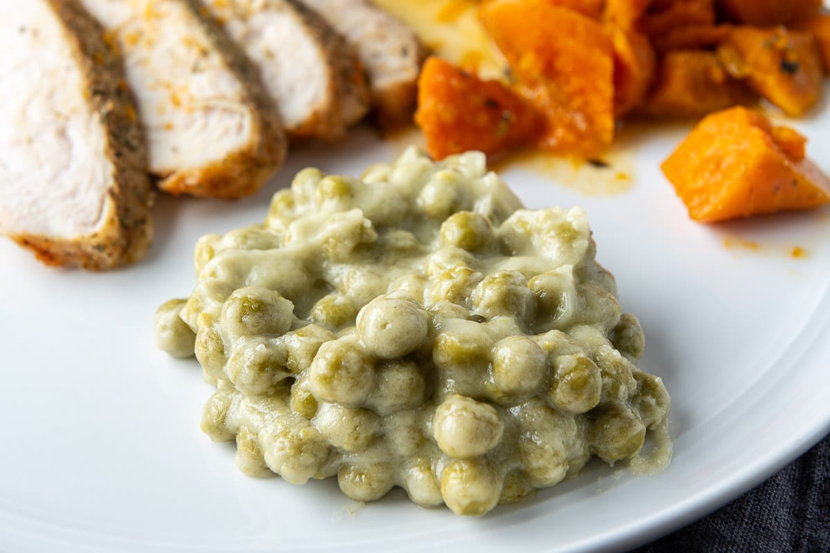 Close up of creamed peas on a plate with meat and carrots