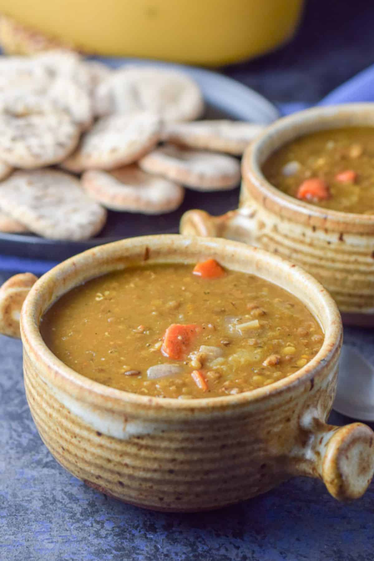 Closer look of the 2 crocks of soup with a plate of pita and the big bowl of soup in the background