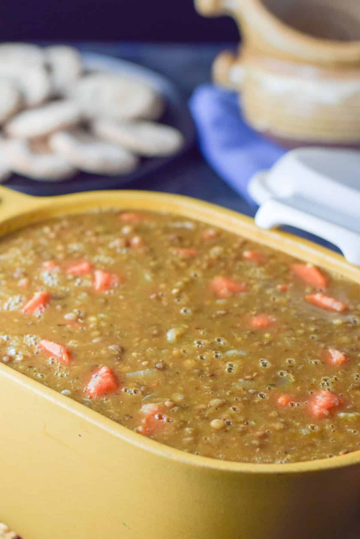 Soup done and in a big mustard colored bowl with crocks and pita rounds in the background