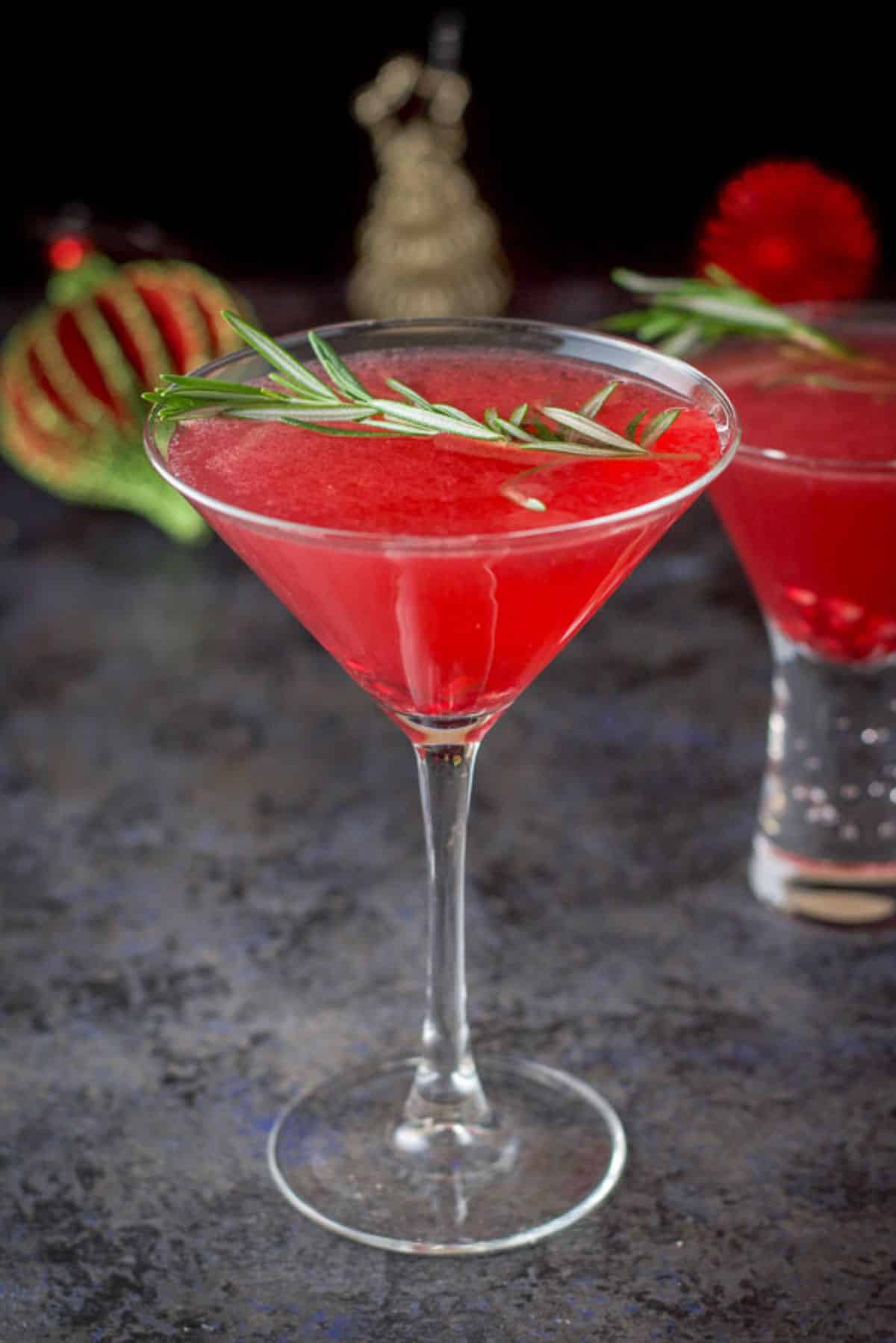 A closer view of the pomegranate cocktail in the tall martini glass with the bubble glass in the background