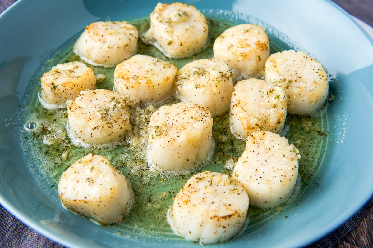 horizontal photo of garlic scallops in a deep dish
