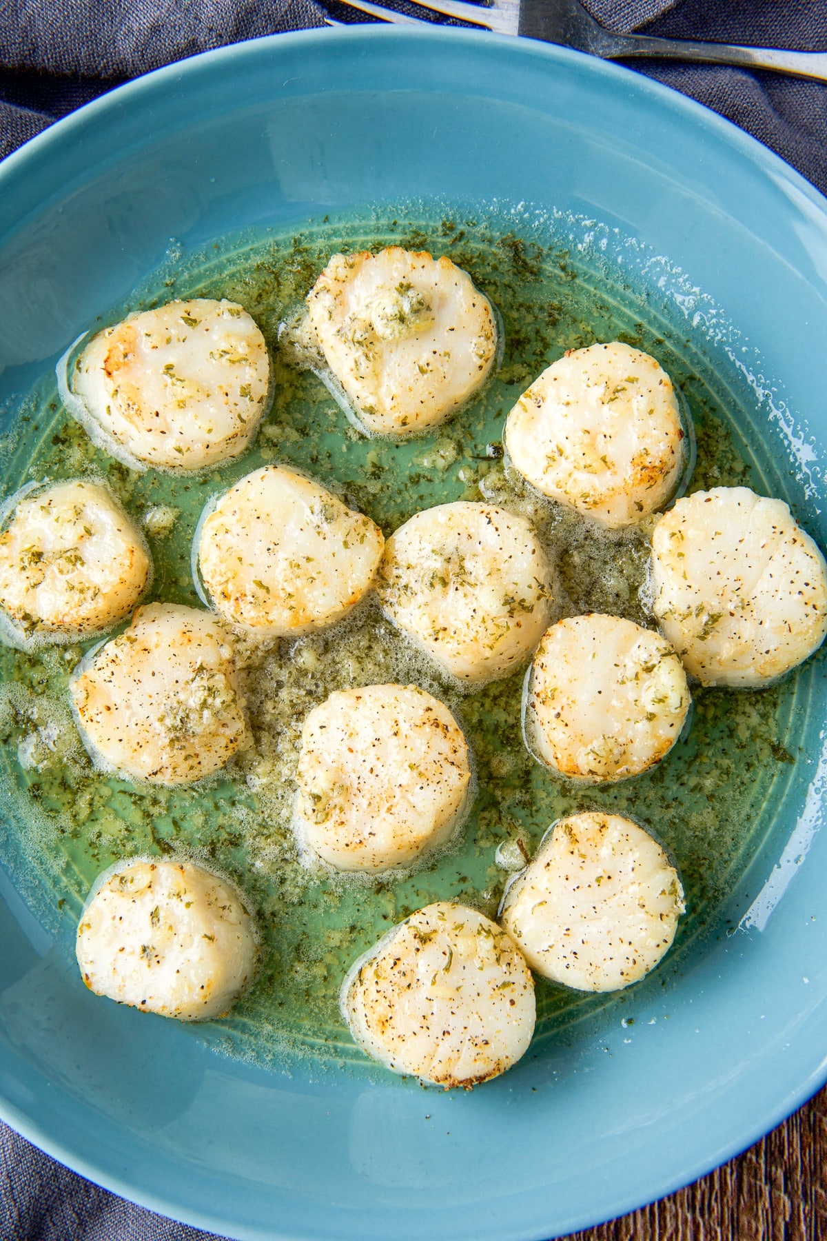 Overhead view of the scallops in the butter sauce in a dish