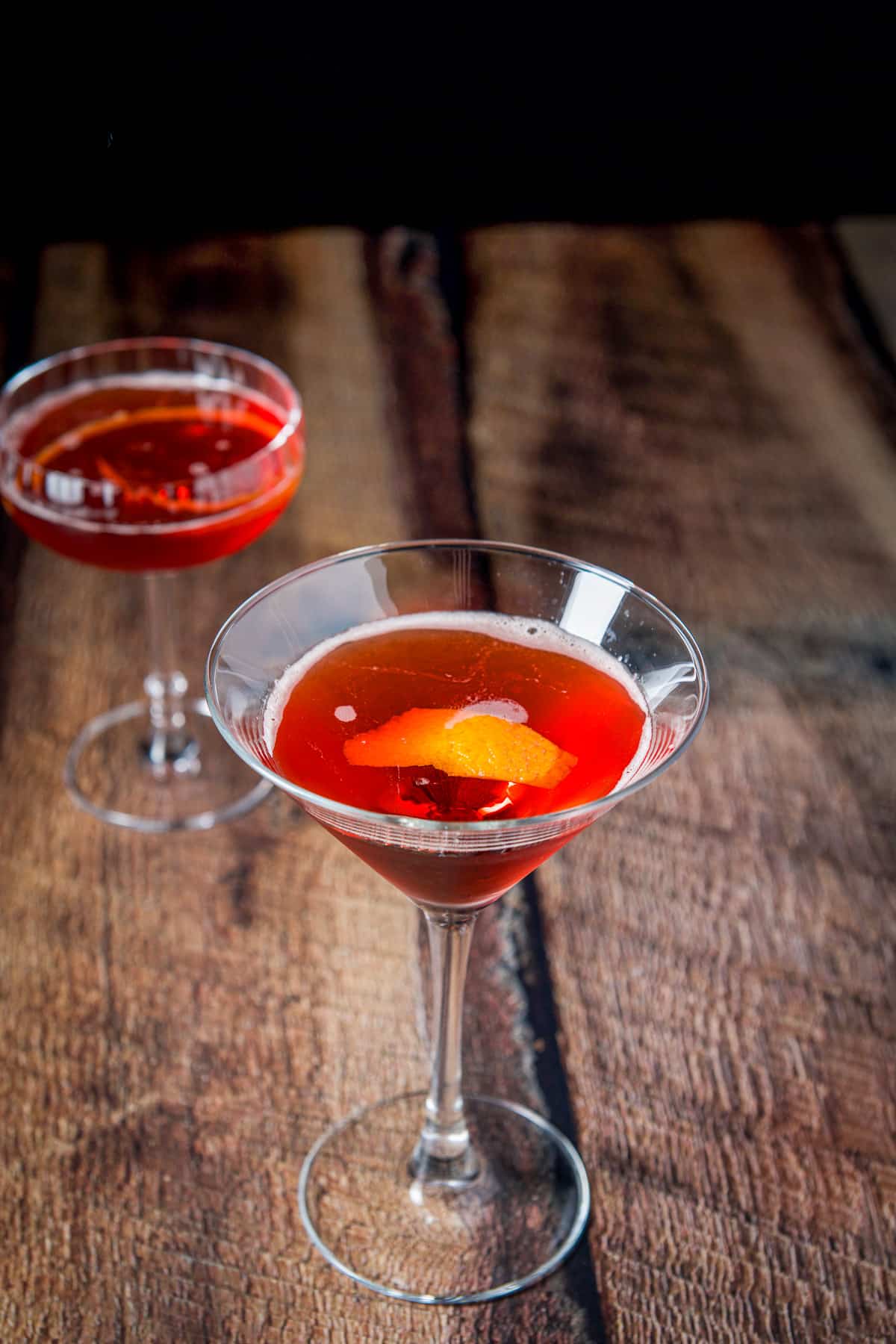 The martini glass with the orange twist in it and a coupe glass in the back with the classic cocktail