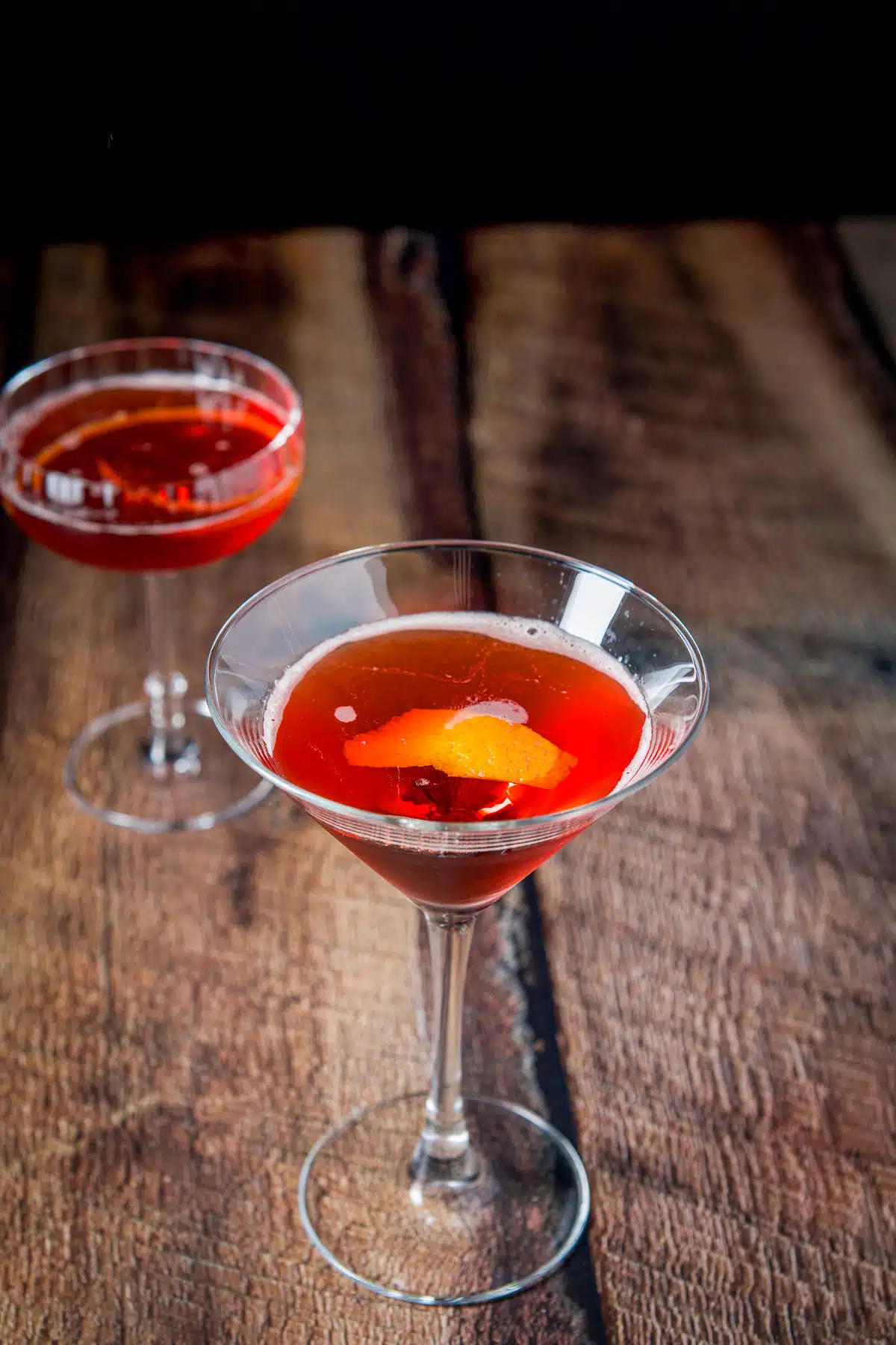 The martini glass with the orange twist in it and a coupe glass in the back with the classic cocktail