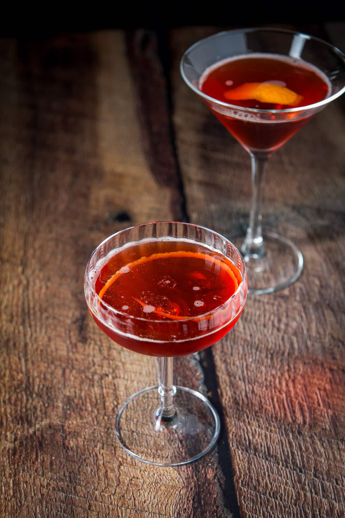 A lemon twist in the cocktail along with the martini glass in the back