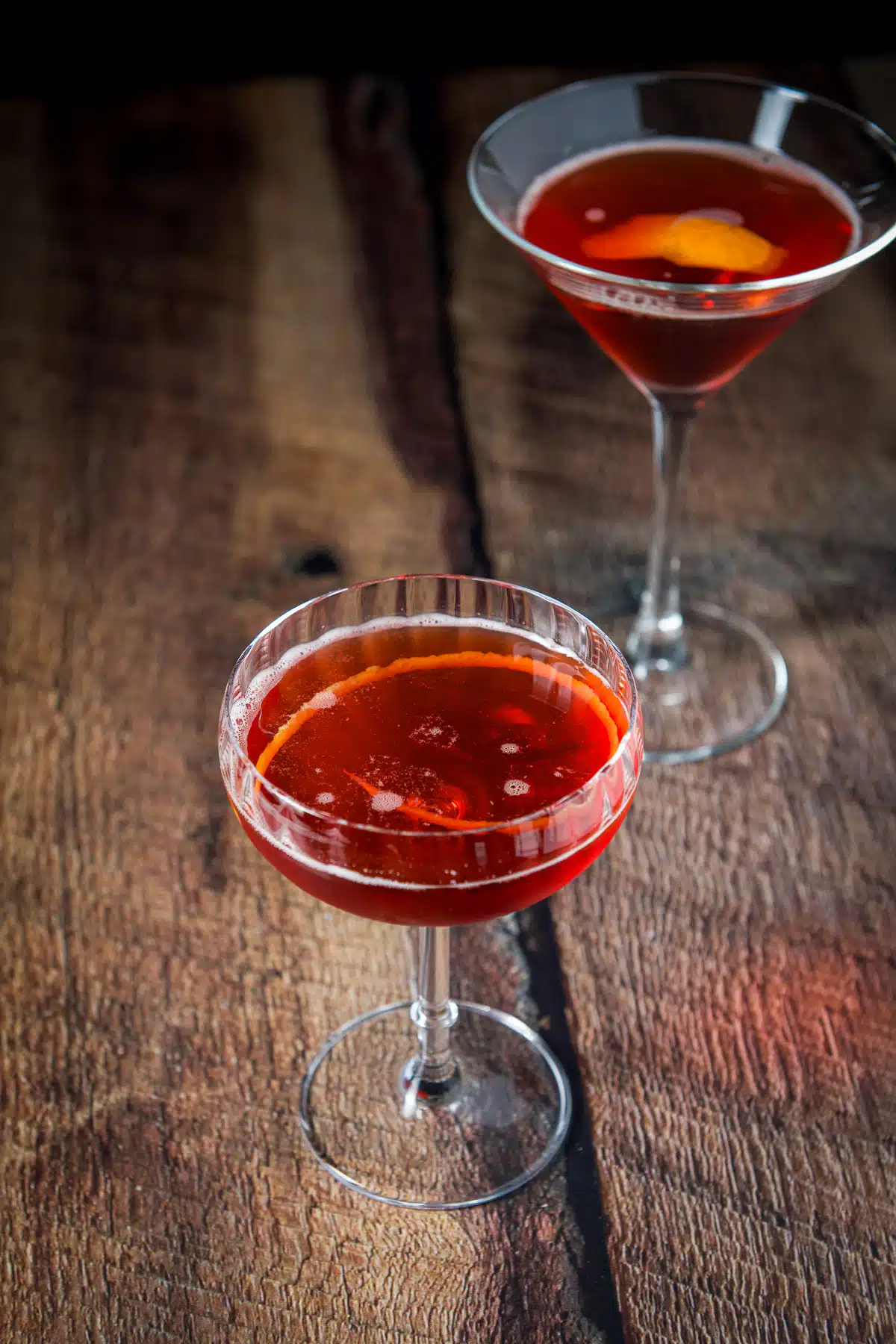 A lemon twist in the cocktail along with the martini glass in the back