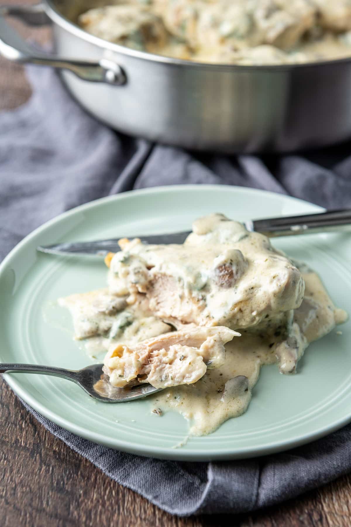A close up of chicken with a white sauce on it. The chicken has been cut and the piece is on a fork